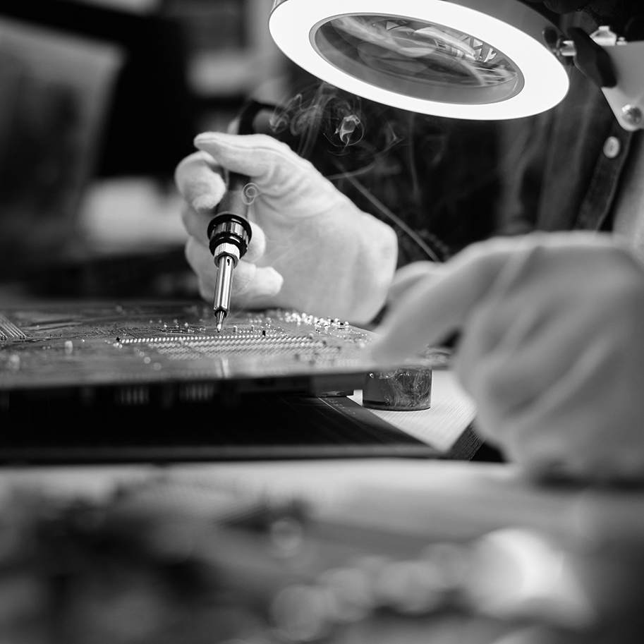 Side view closeup of unrecognizable repairman fixing circuit board in tech workshop, copy space